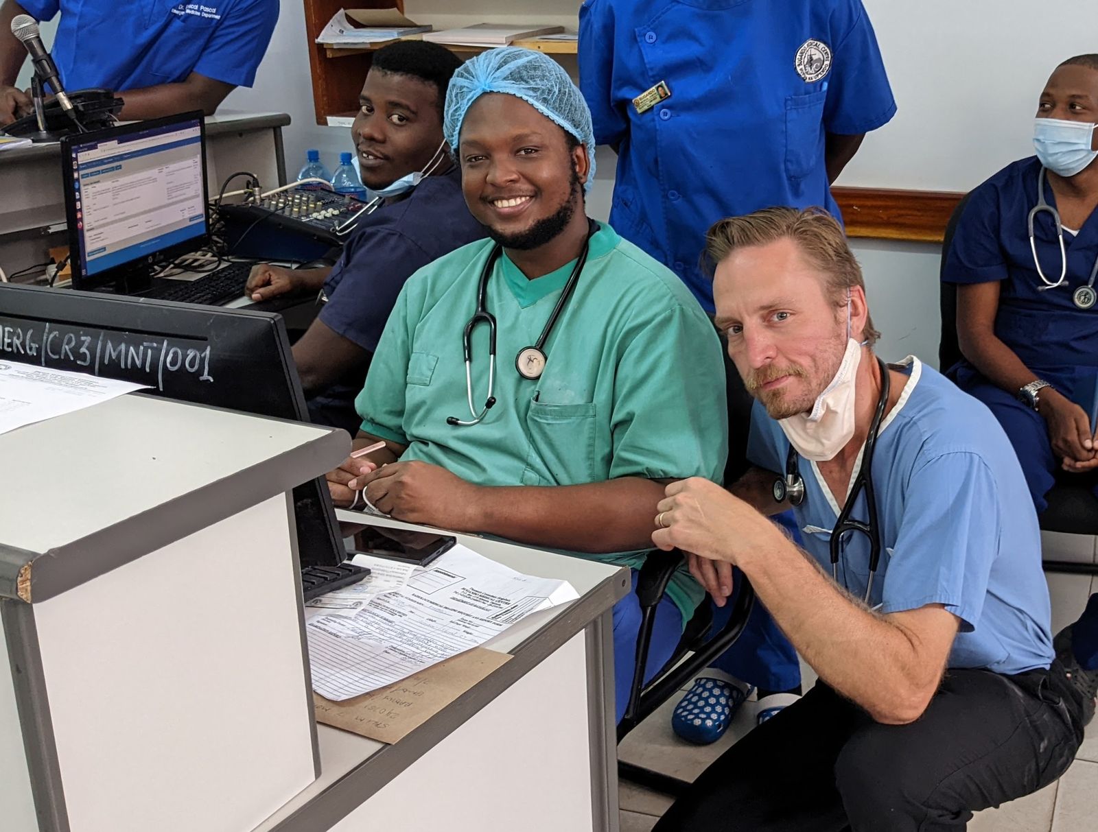Dr. Deus Mselle in green scrubs at a workstation in the Bugando emergency department