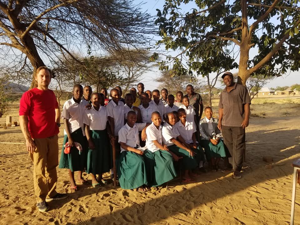 Kibakwe Secondary School scholarship students seated outdoors with a teacher