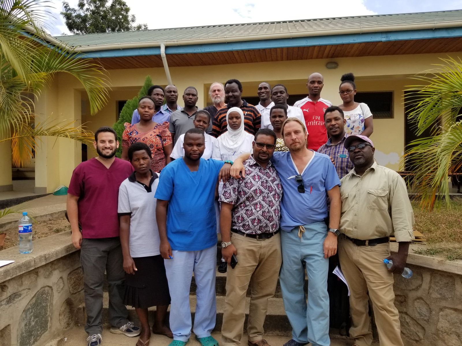 Large group of Tanzanian and visiting clinicians standing outside a hospital building