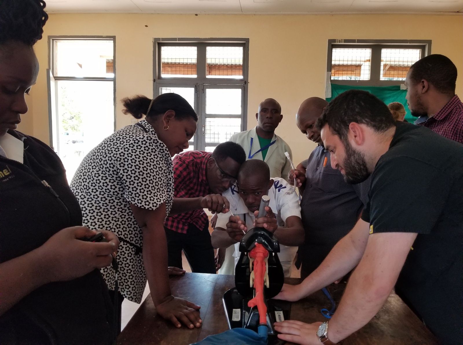 Tanzanian doctors and nurses practicing a procedure on a training model with a visiting emergency physician